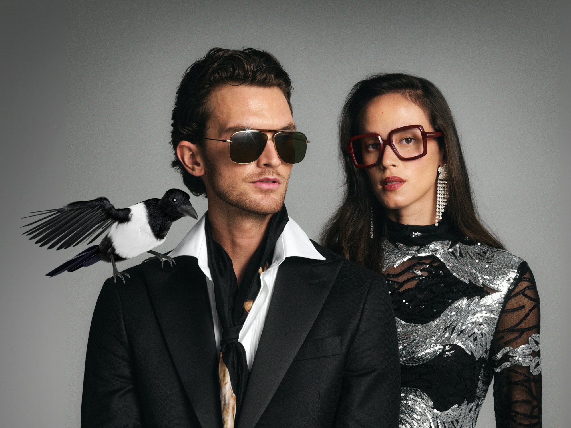 Mann med solbriller og dame med briller, fugl på skulderen til herre