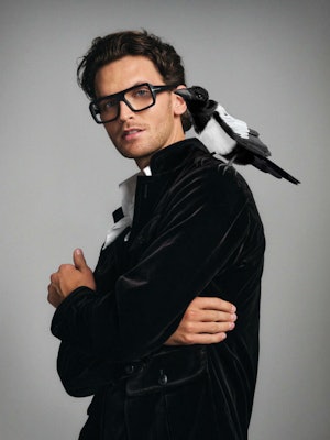 Herre med kraftige briller og fugl på skulderen