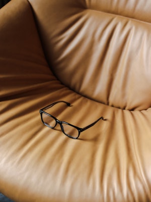 Svart brille i brun skinnstol