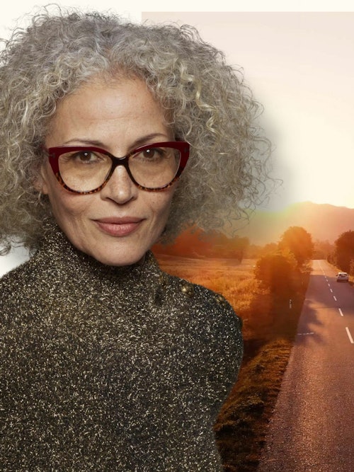Dame med briller foran et bilde av en landevei