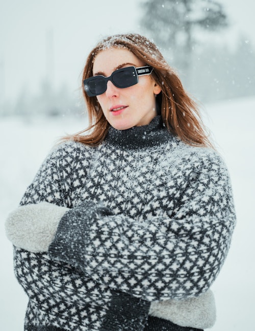 Jente i genser med solbriller mens det snør