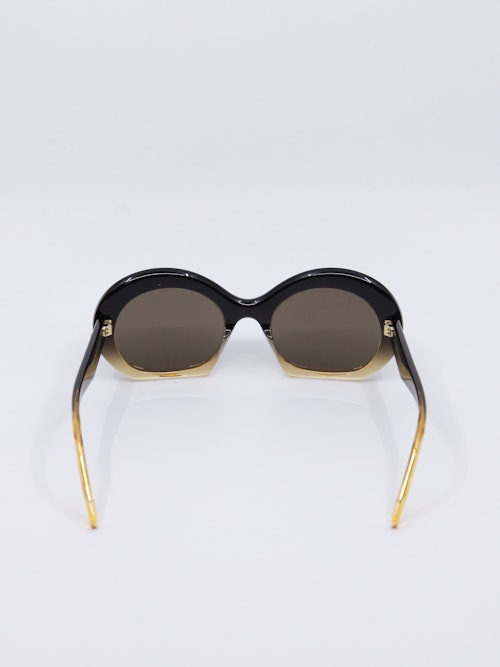 Solbrille i svart og gylden farge og med en oval passform