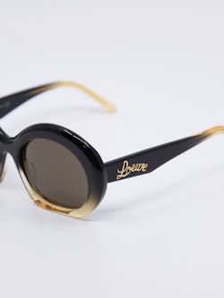 Solbrille i svart og gylden farge og med en oval passform