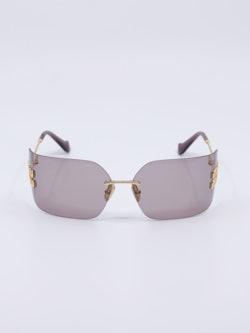 Solbrille uten ramme med rosa glass og metallstenger i gull