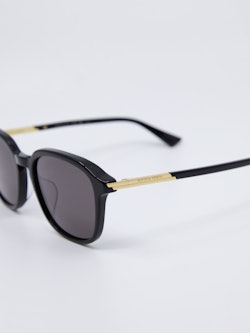 Svart solbrille med gull-detaljer på brillestengene
