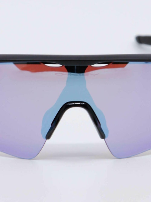 Oakley sportsbrille i lillatoner og rødlig farge