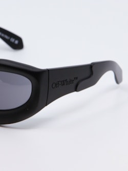 Oval solbrille i svart med mørkegrå glass