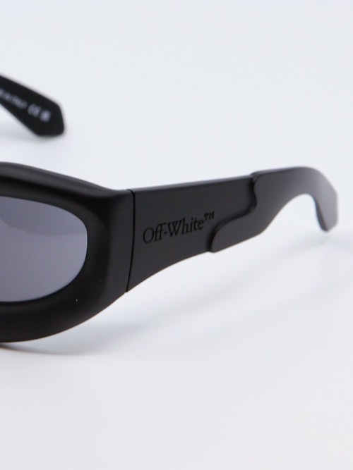 Oval solbrille i svart med mørkegrå glass