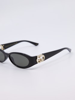 Smal, svart solbrille med vintage-design og gull-logo på brillestengene