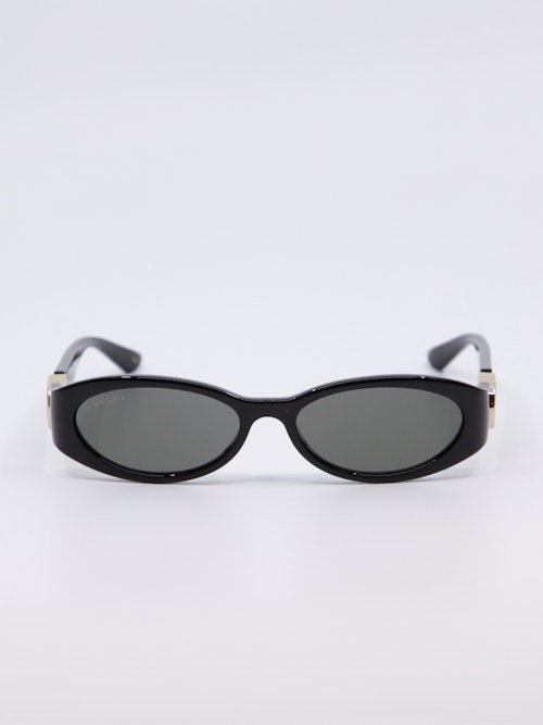 Smal, svart solbrille med vintage-design og gull-logo på brillestengene