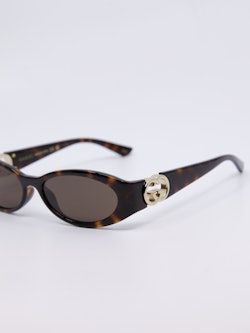 Smal, brun solbrille med vintage-design og gull-logo på brillestengene