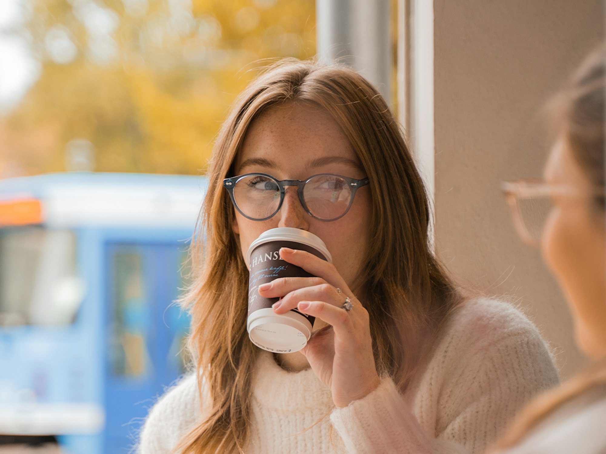 Kvinne drikker kaffe med trikken utenfor vinduet