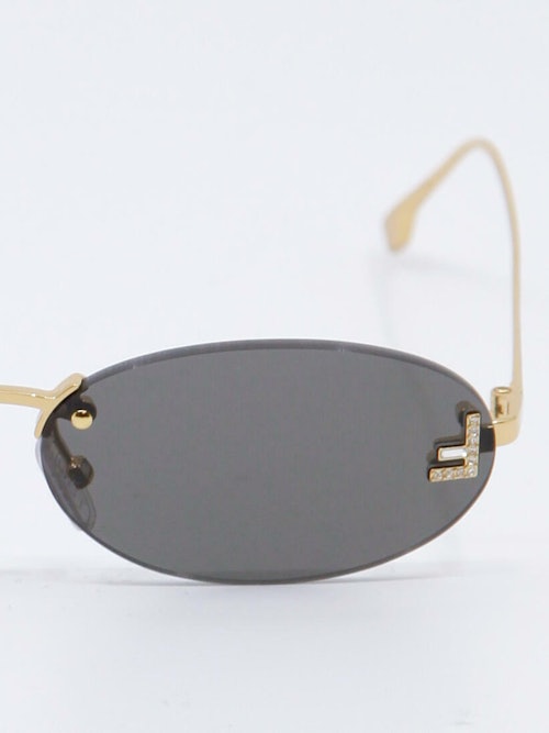 Smale, ovale solbriller i svart og gull, nærbilde