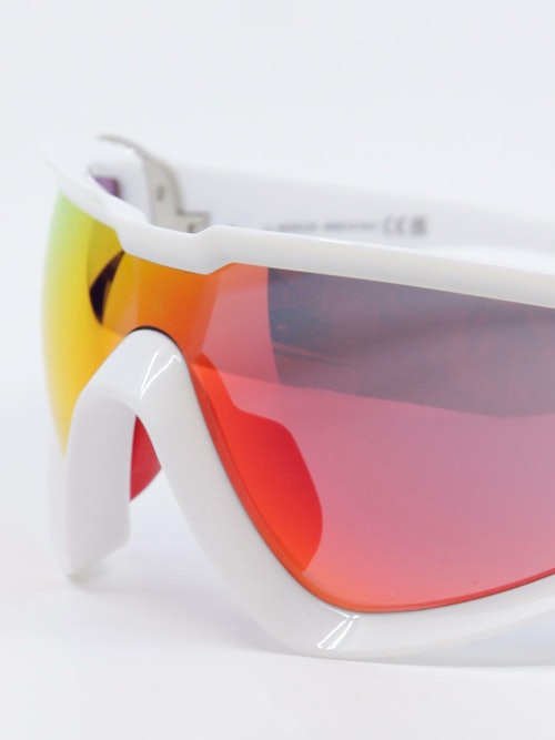 Tykke sportsbriller i rød og gulfarget glass med hvit ramme, nærbilde