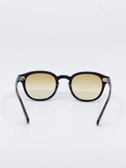 Rund solbrille med sort ramme og  karamell fargede, gradert glass, bilde bakfra