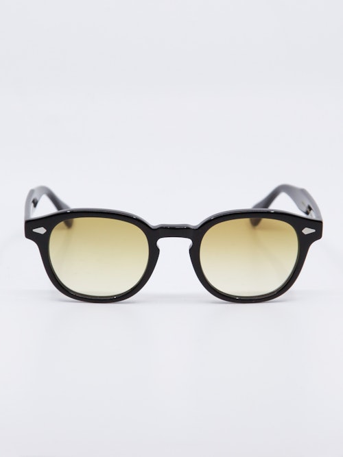 Rund solbrille med sort ramme og  karamell fargede, gradert glass, bilde forfra