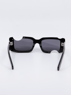 Sort solbrille med cut-out design og Off-White logo på brillestengene, bilde bakfra