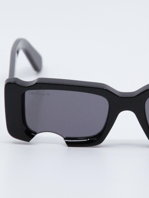 Sort solbrille med cut-out design og Off-White logo på brillestengene, nærbilde