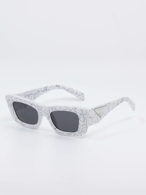 Hvit solbrille med marmordesign og svarte glass, bilde fra siden