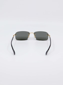 Sort solbrille fra Gucci med gull-detaljer på nesebro og brillestenger, bilde bakfra