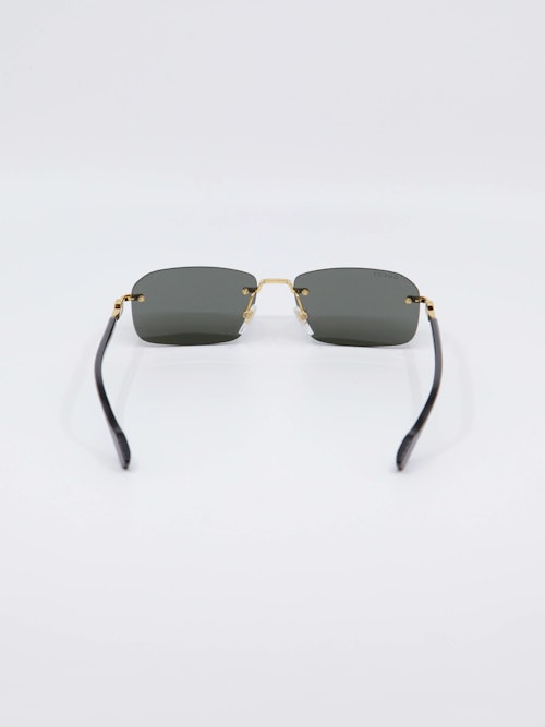 Sort solbrille fra Gucci med gull-detaljer på nesebro og brillestenger, bilde bakfra