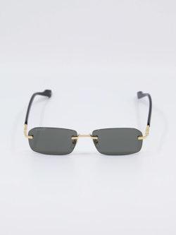 Sort solbrille fra Gucci med gull-detaljer på nesebro og brillestenger, bilde forfra