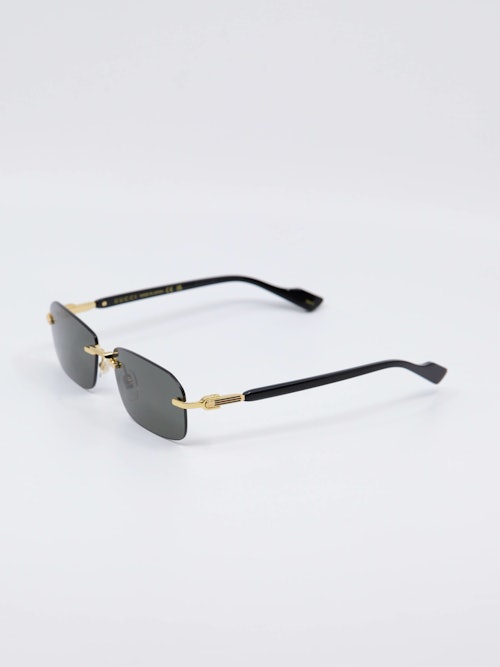 Sort solbrille fra Gucci med gull-detaljer på nesebro og brillestenger, bilde fra siden