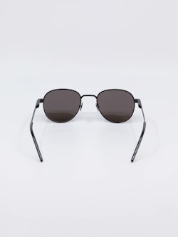 Svart solbrille fra Saint Laurent, runde glass og tynne brillestenger, bilde bakfra